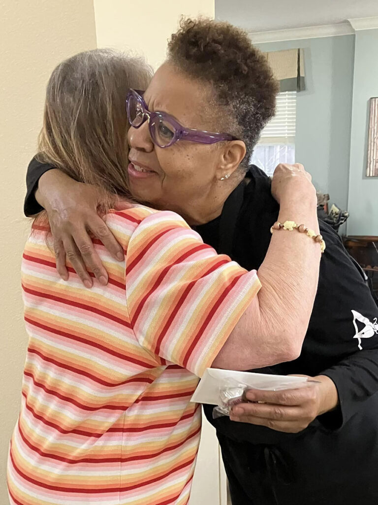 An elderly resident and a staff member showing affection through a hug