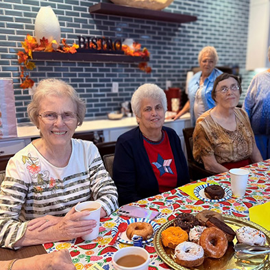 Senior women at The Fremont enjoy donuts and beverages in the bistro.