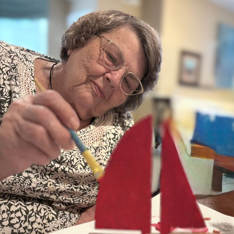 A senior woman smiles serenely during a painting project.