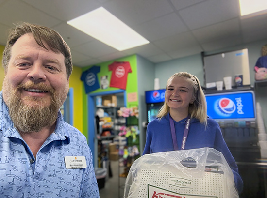 A team member from The Fremont Senior Living smiles alongside a young woman at a local business.