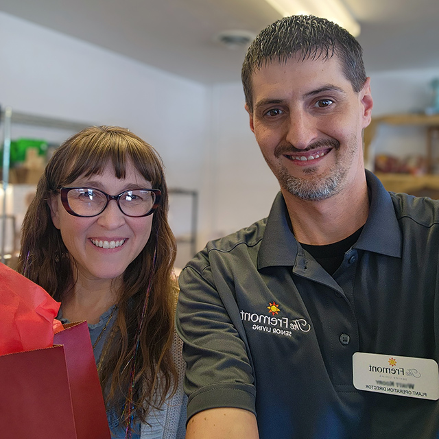 A team member from The Fremont smiles alongside a woman from a local business, holding a gift bag.