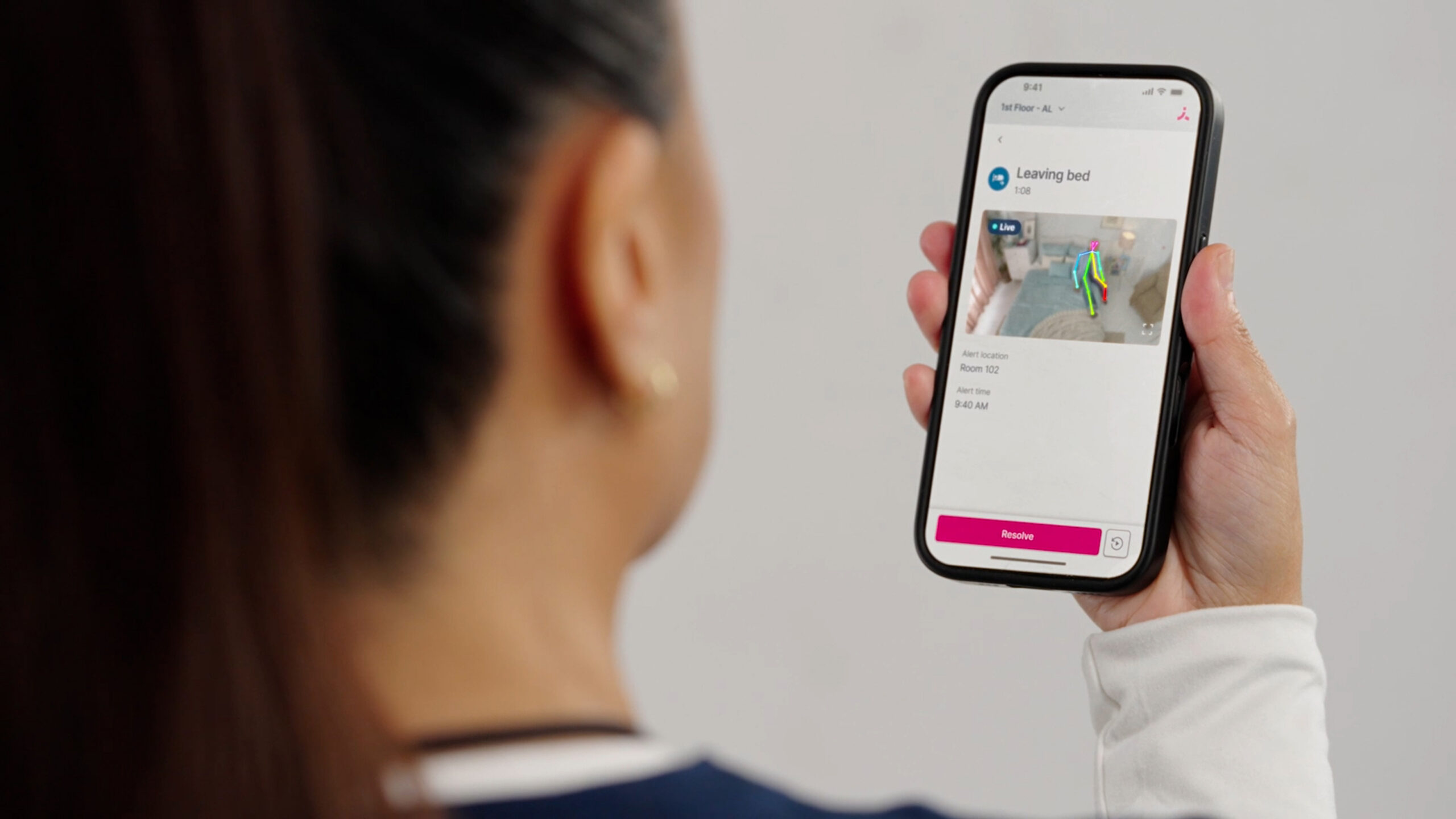 Care team member views an Inspiren alert on a smartphone showing a resident leaving bed.